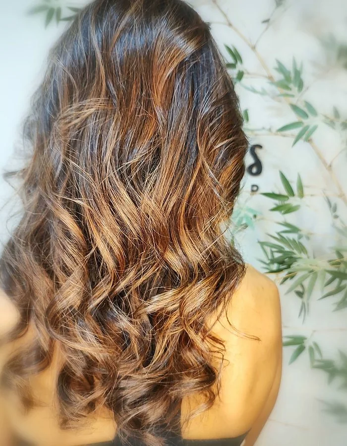 Cabelos com ondas e iluminação em tons castanhos e dourados